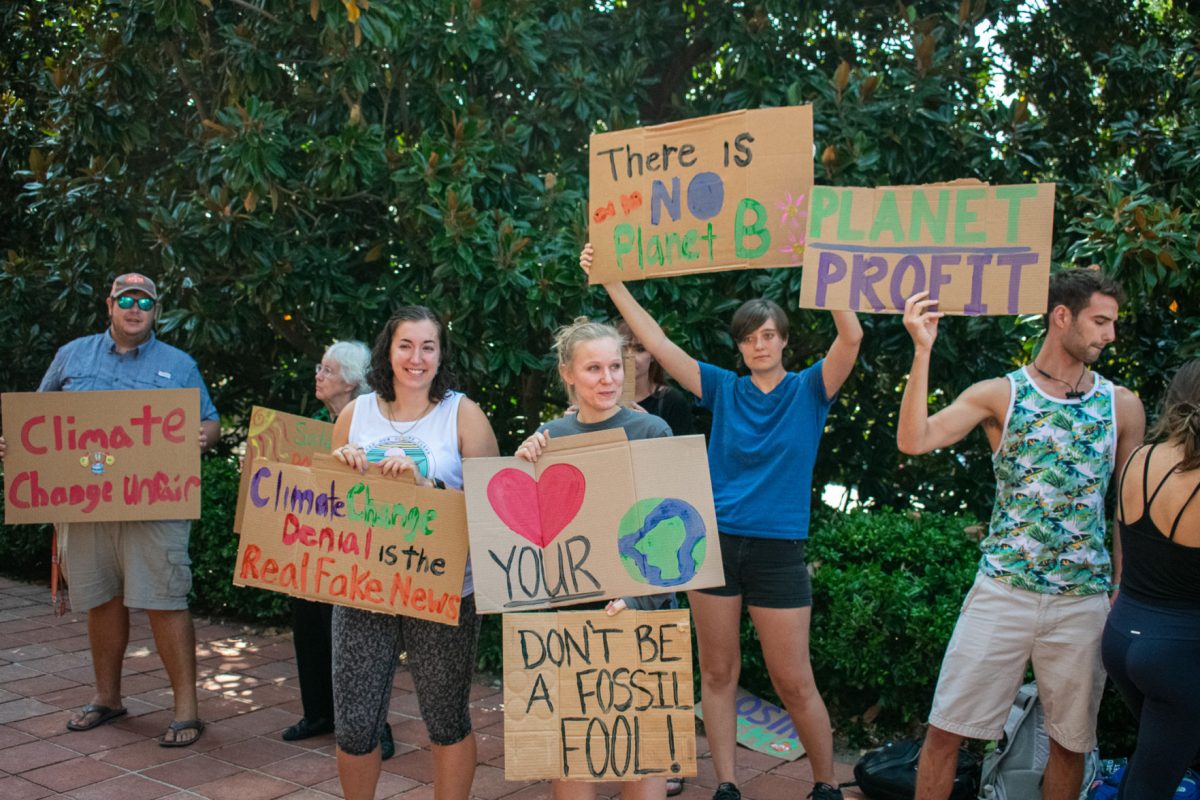 Students protesting climate change hold signs on the side of Library Bridge.