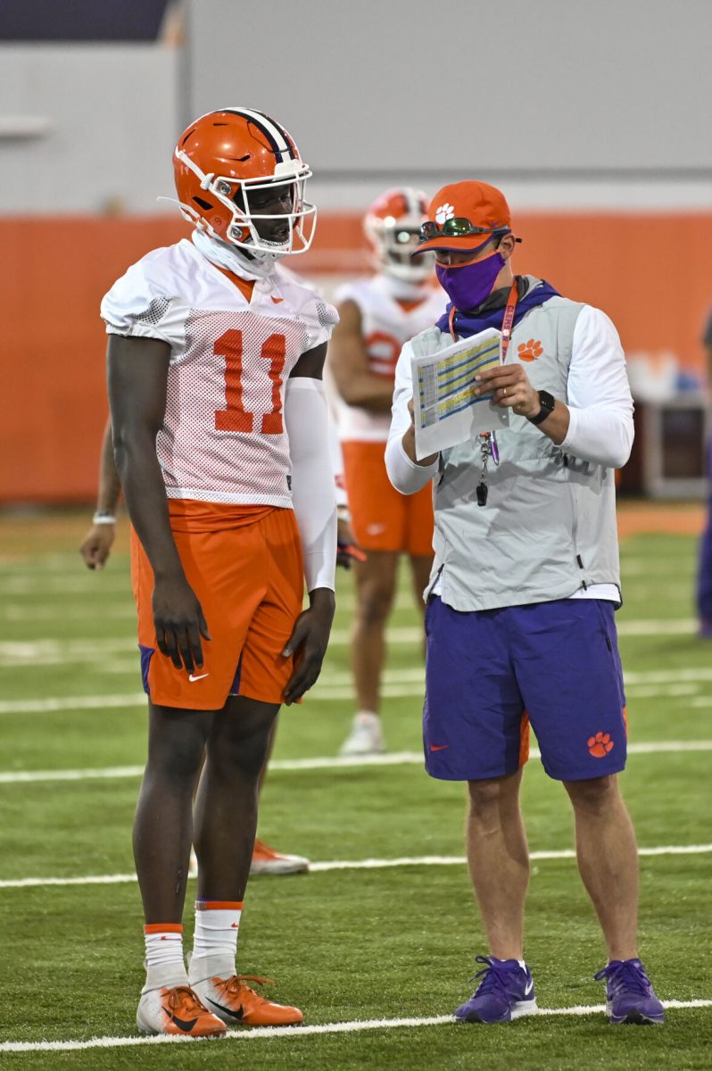 <p>Coach Tyler Grisham (right) discusses a drill with freshman wide receiver Ajou Ajou (11) during fall football camp.</p>