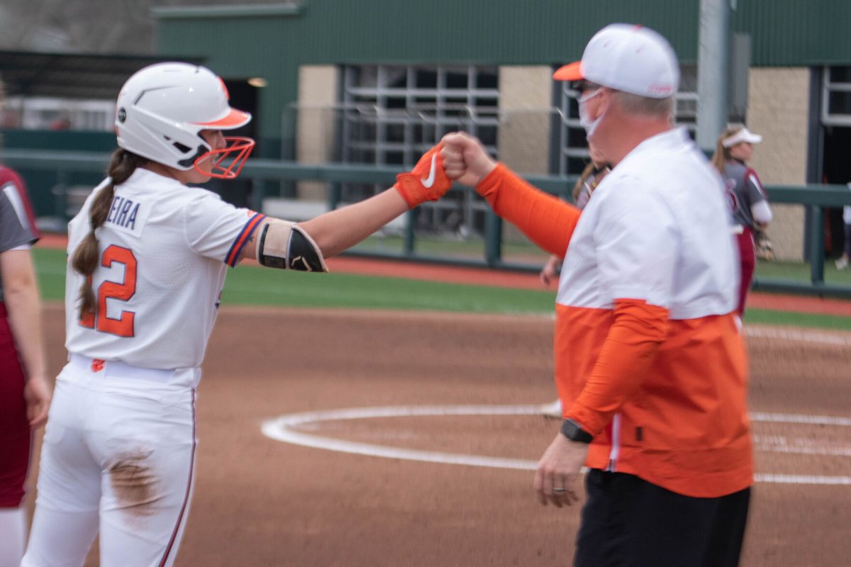 Redshirt senior second baseman Cammy Pereira knuckle touches head coach John Rittman at third base.