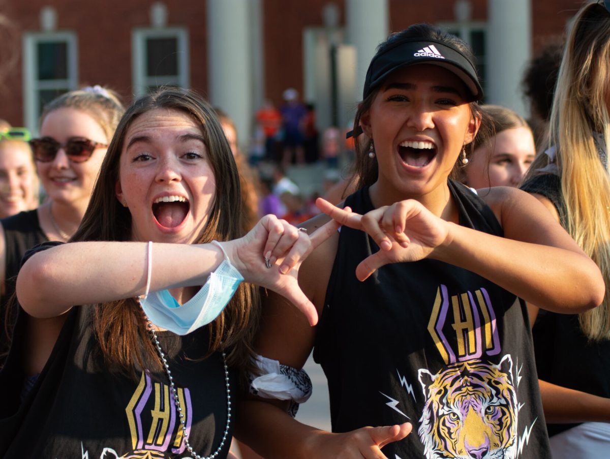 Two friends in the Chi Omega sorority cheerfully pose among their other sisters during the parade.