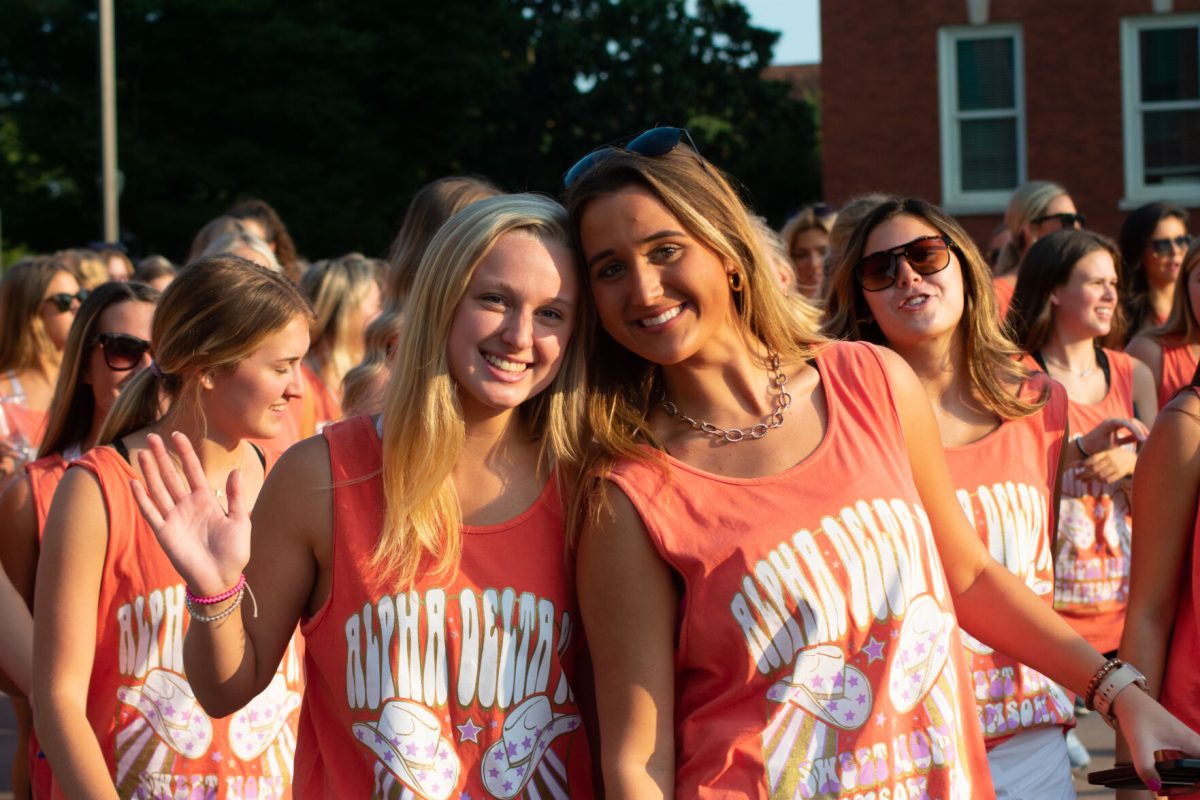 Two members of Clemson's chapter of Alpha Delta Pi (&#913;DPi) give a &#128075; to the camera as they march.