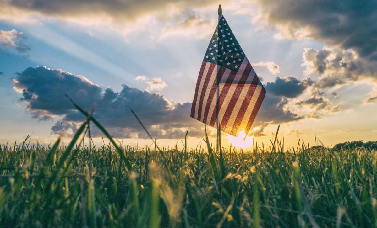 American Flag in ground as sun sets in background