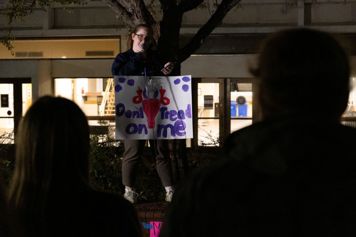 Maggie Packard speaks to the crowd holding a protest sign