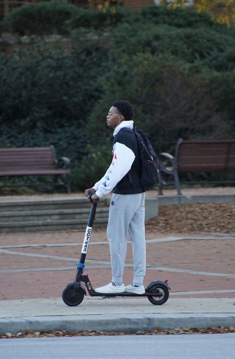 Clemson student rides e-scooter through downtown.