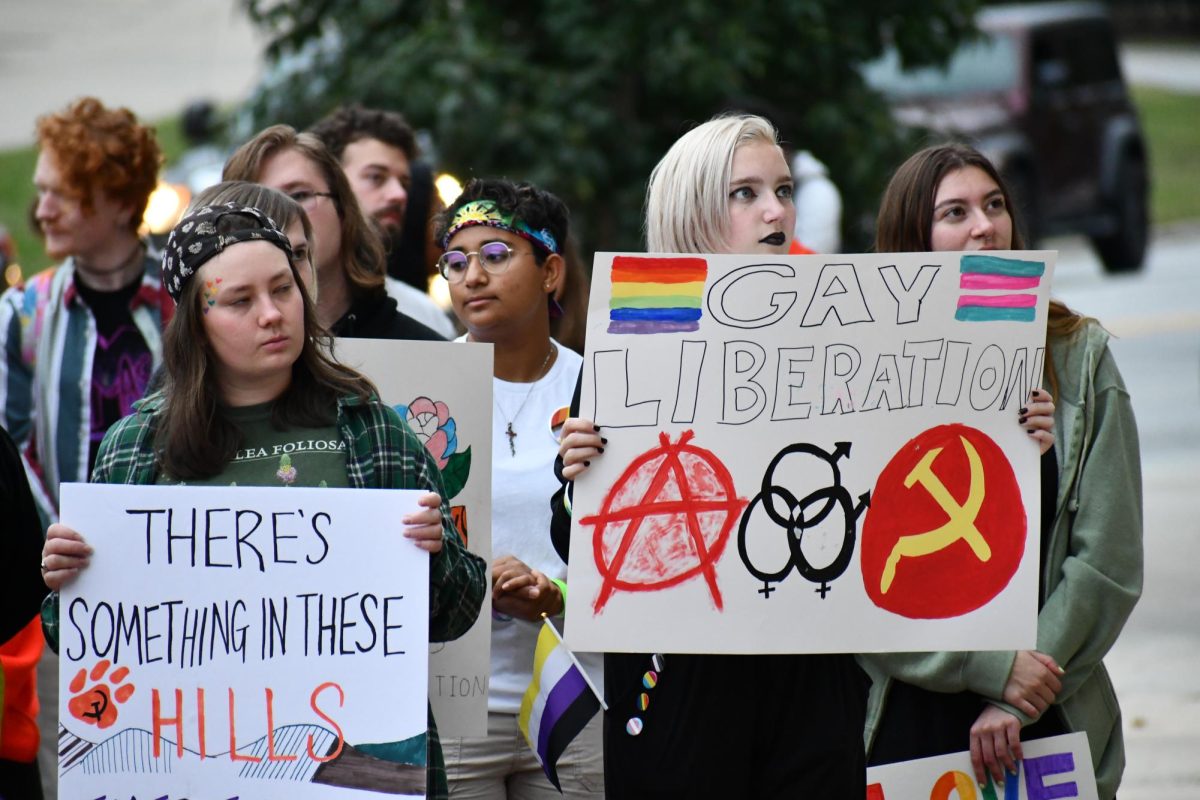 Protesters at the Take Back Pride march on Oct. 11 carry signs depicting communism and anarchy symbols beside pro-pride imagery. 