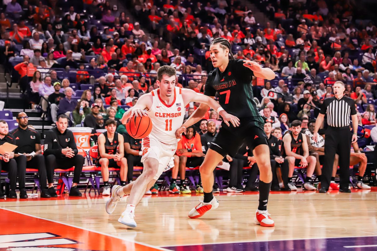 Clemson guard Joseph Girard III (11) dribbles past Miami defender Kyshawn George (7) in Clemsons win over the Hurricanes at Littlejohn Coliseum on Feb. 14, 2024.