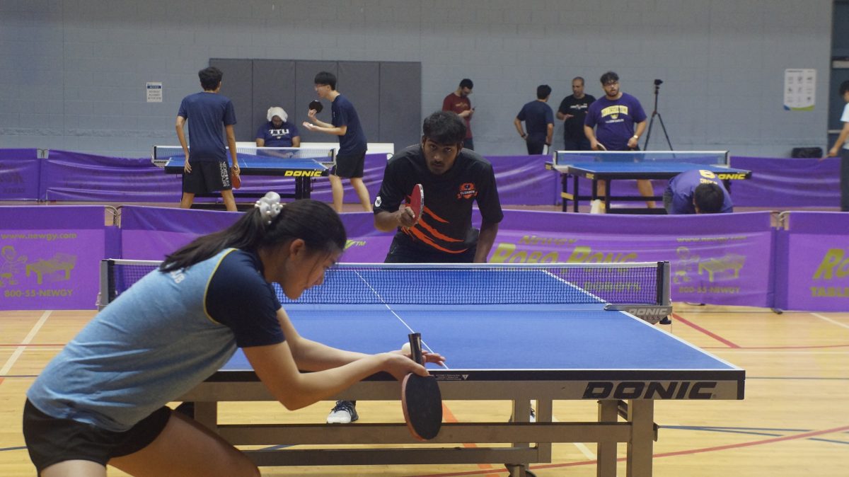 Members of the Table Tennis club get ready to serve the ball to their opponent in a competitive match.