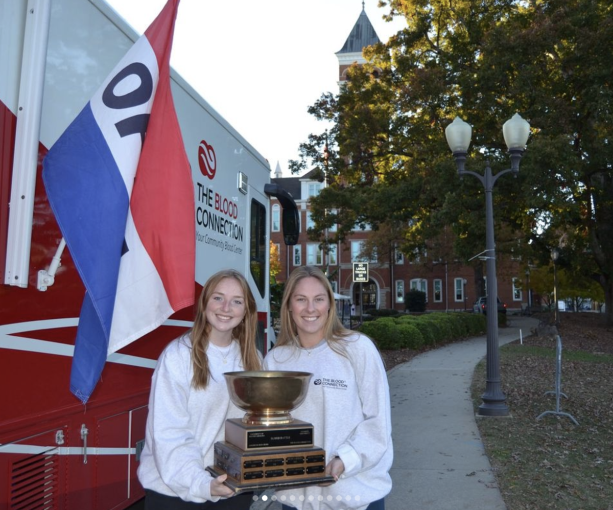 Blood Bowl cochairs Caroline Graybeal and Lindsey Schmidt pose with the Blood Bowl trophy.