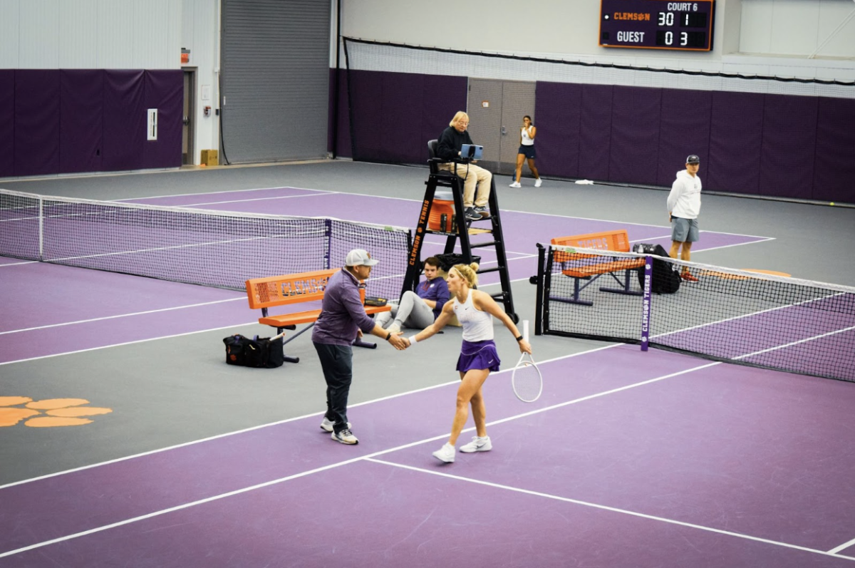 Annabelle Davis celebrates with head coach Boomer Saia after winning her set against Liberty University’s Maria Turchetto. 