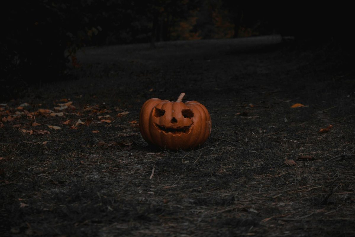 A carved pumpkin sitting in a field.