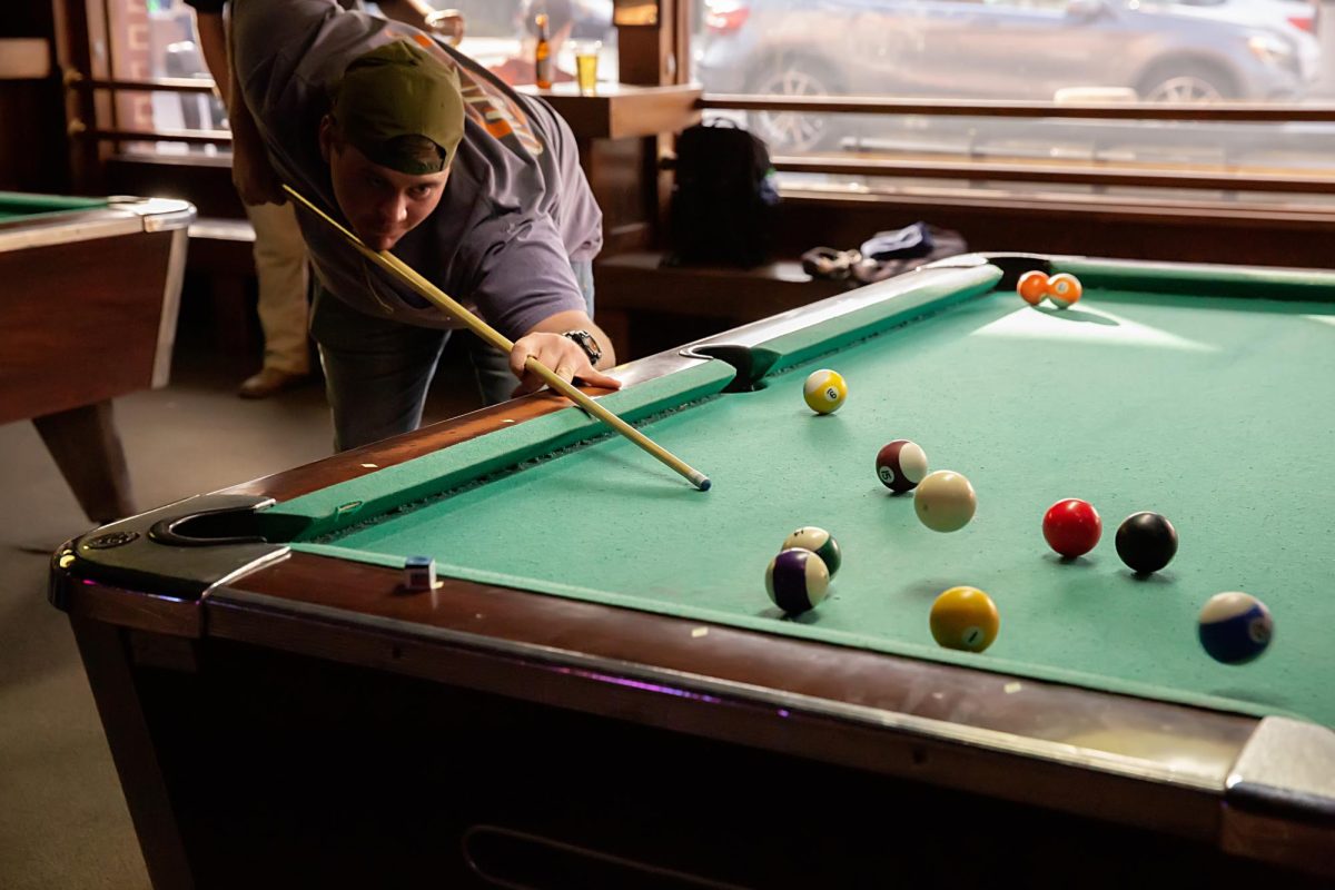 A pool player at Tiger Town Tavern sinks a striped ball into the corner pocket.